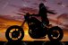 24478706-une-femme-sur-une-moto-dans-le-coucher-du-soleil-avec-son-bras-en-arrière-.jpg
